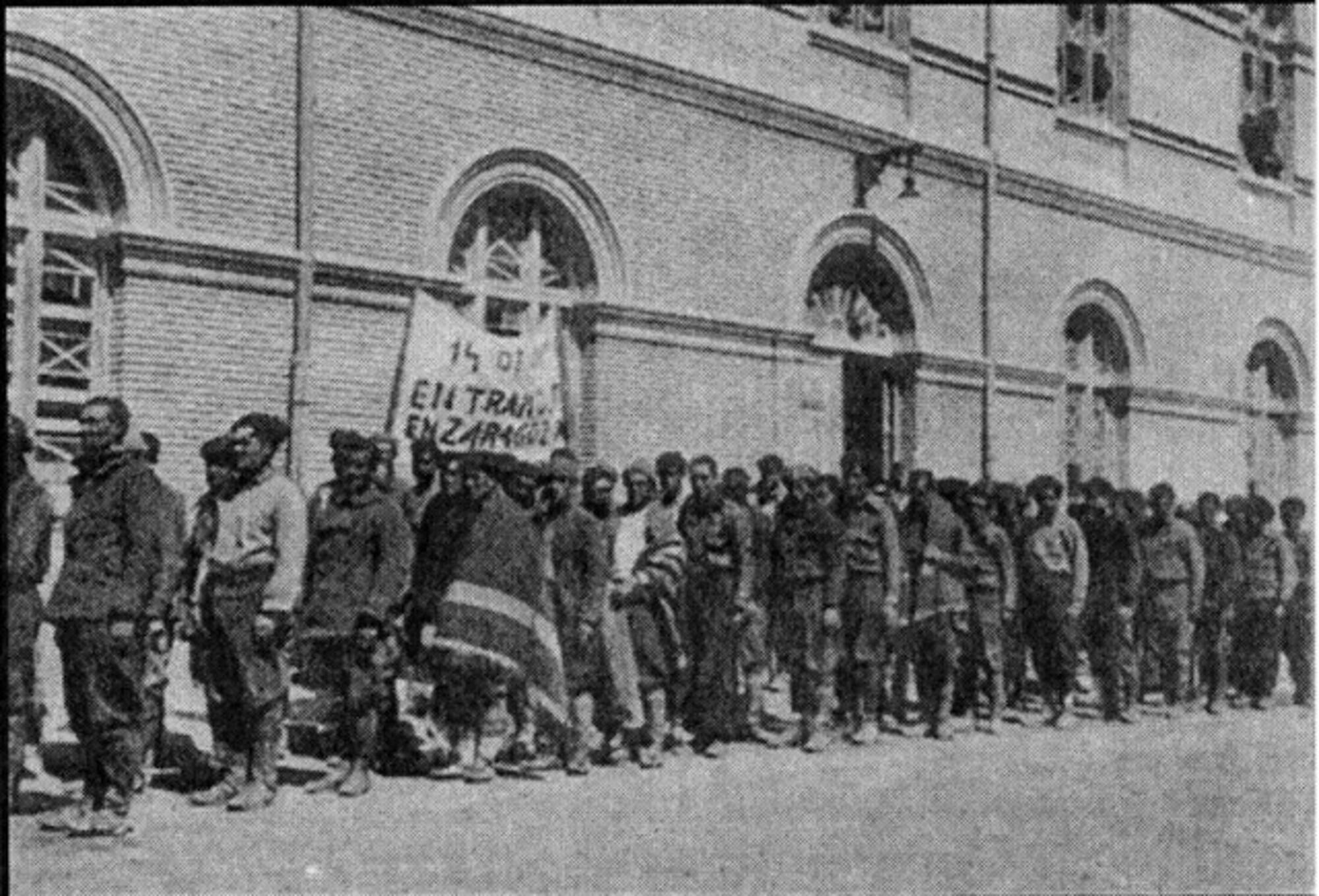 Prisioneros llegando a San Juan de Mozarrifar con un cartel que lee “Entramos en Zaragoza” el 14 de mayo de 1938